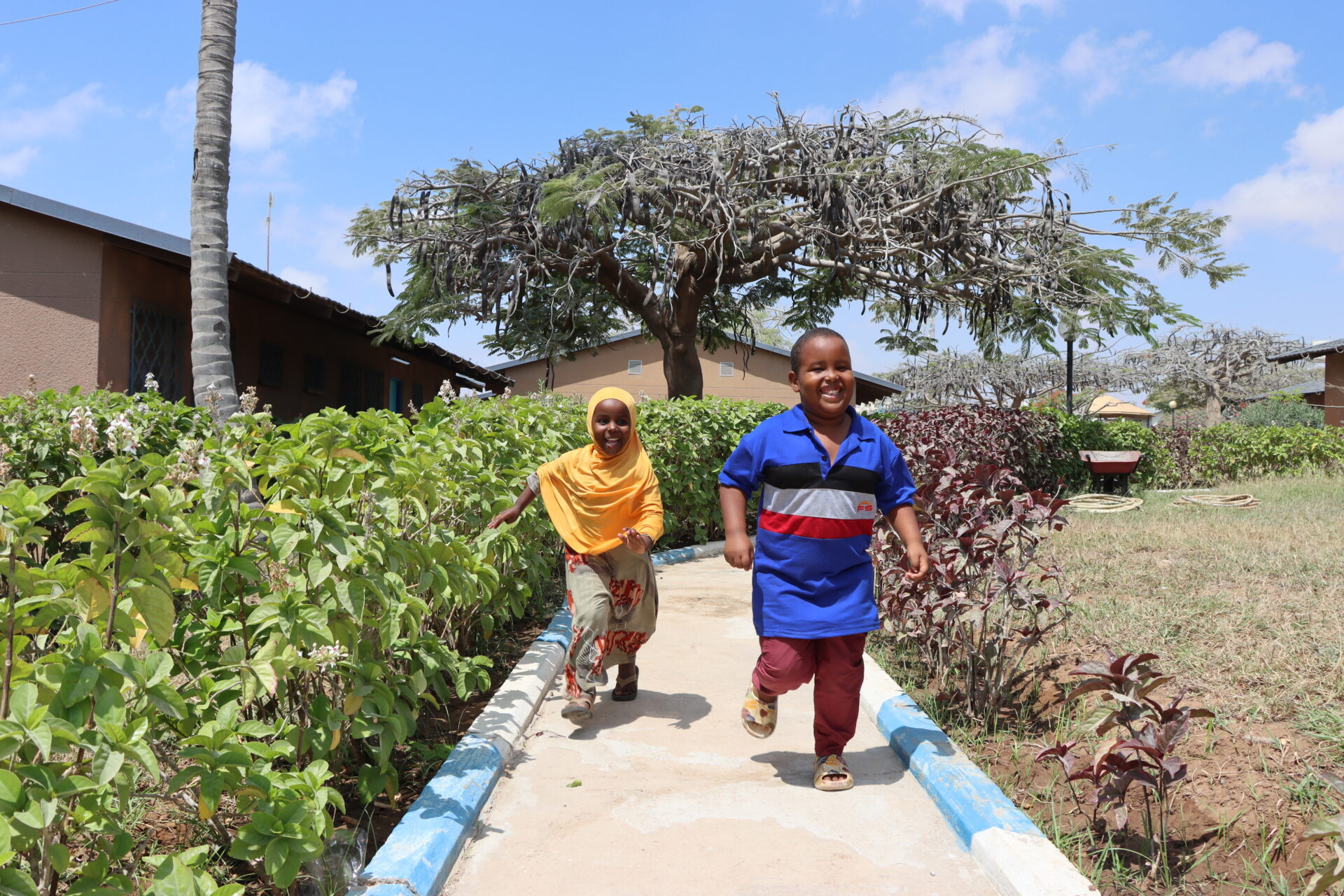 dreng og pige løber, have med træer, sos børnebyerne somalia