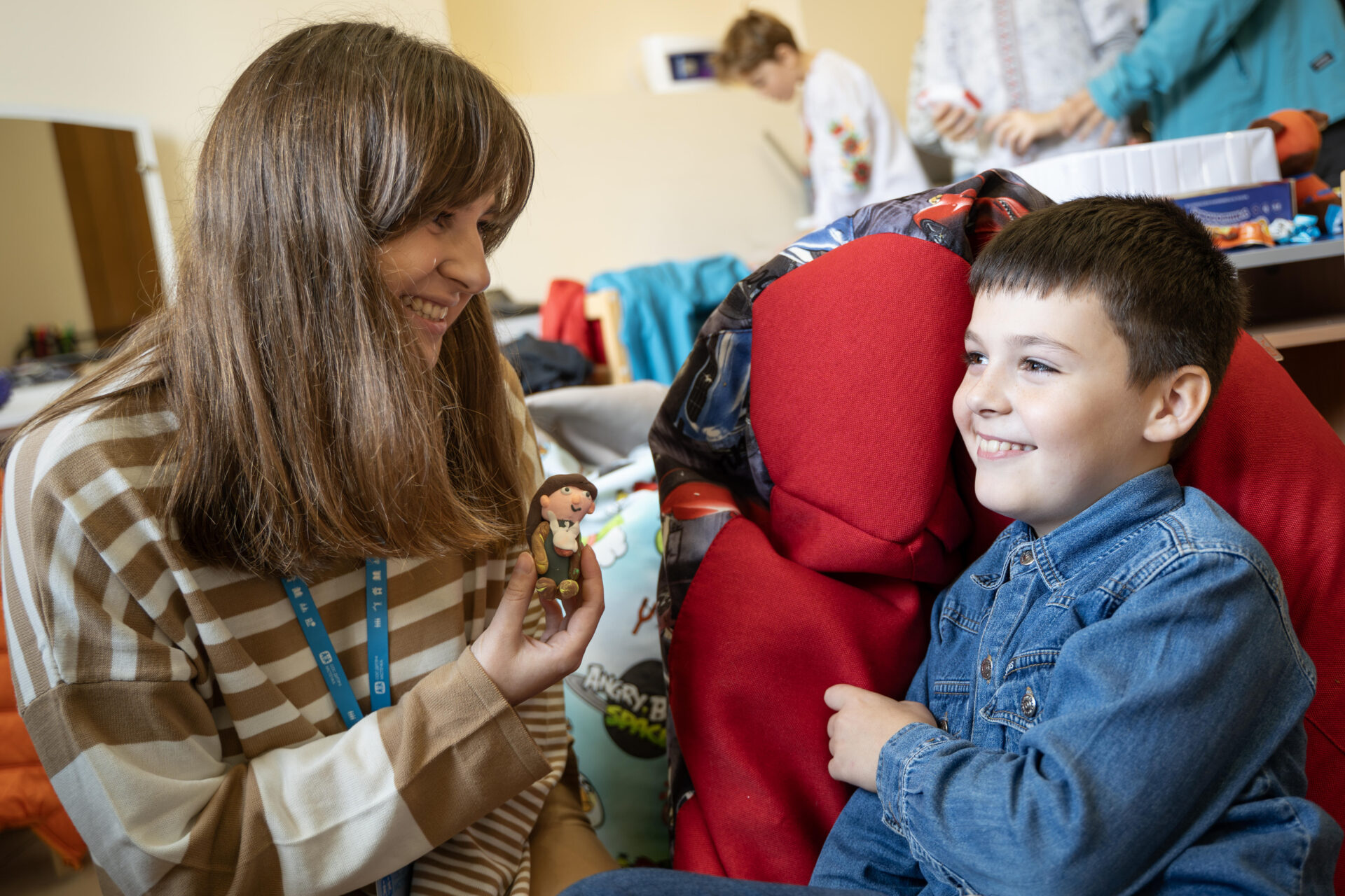 Lille dreng og voksen sidder med en dukke i et kreativt område