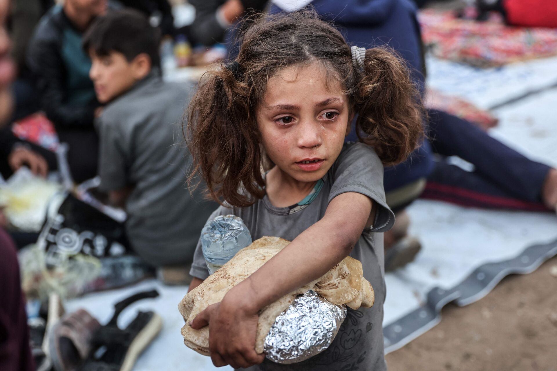 En lille pige bærer på en pakke mad i Gaza.