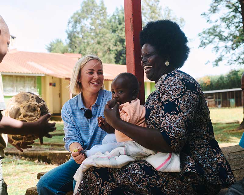 Billedet viser SOS-ambassadør Cille Fjord, der besøger en SOS-familie i Kenya. På billedet er også en SOS-mor og en lille baby på otte måneder.