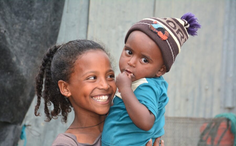 Stor smilende pige bærer mindre barn.