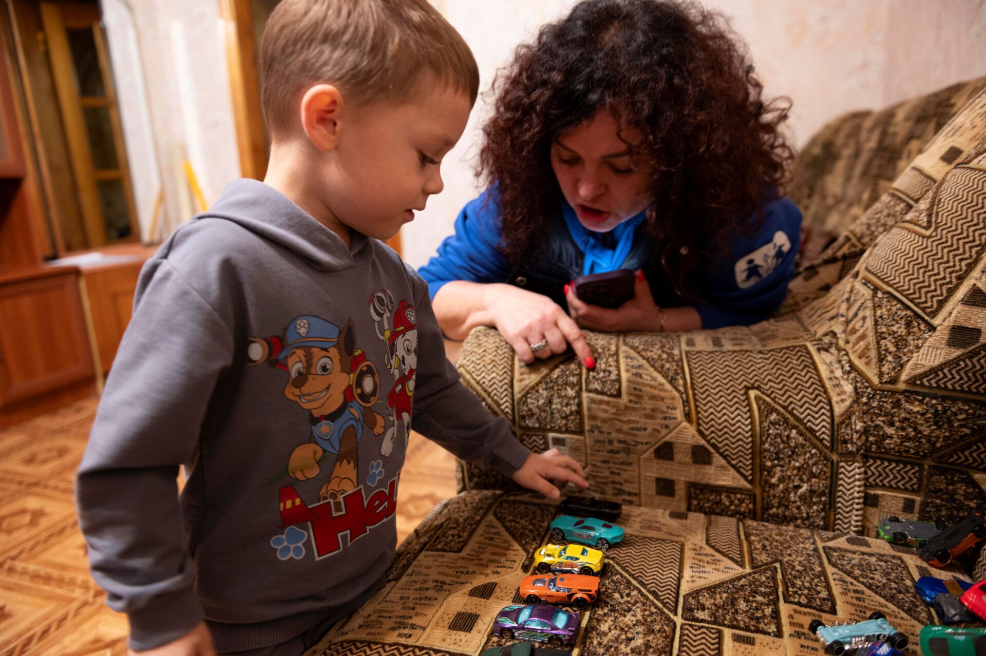 Vanya fra Ukraine viser sine legetøjsbiler til en medarbejder fra SOS Børnebyerne