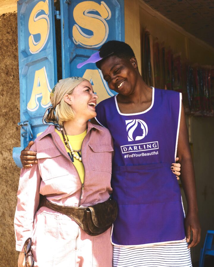Iværksætter Cille Fjord og frisør Coletta Airo står sammen foran en frisørsalon i Kenya.