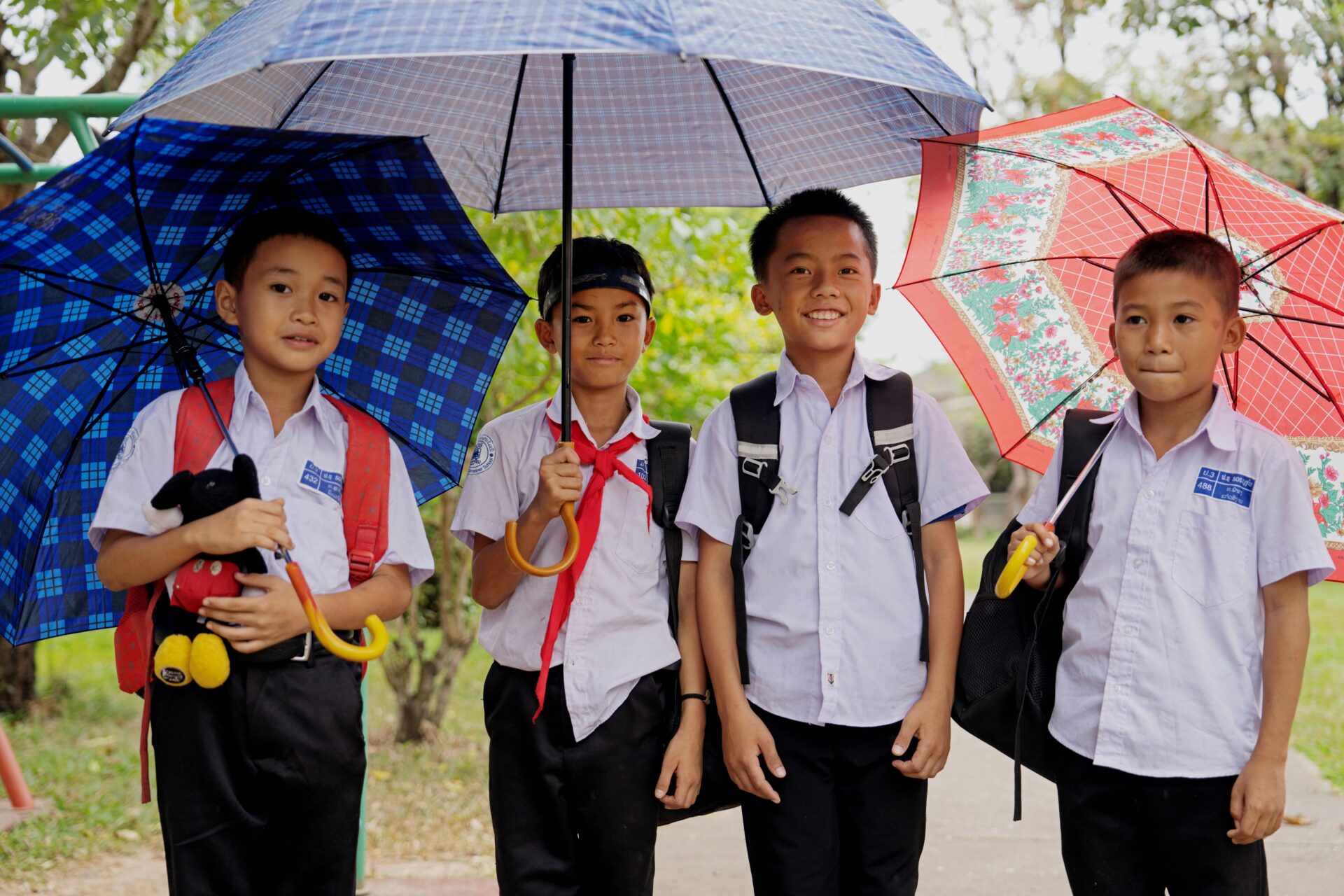 drenge fra børnebyen på vej i skole med paraplyer, Laos